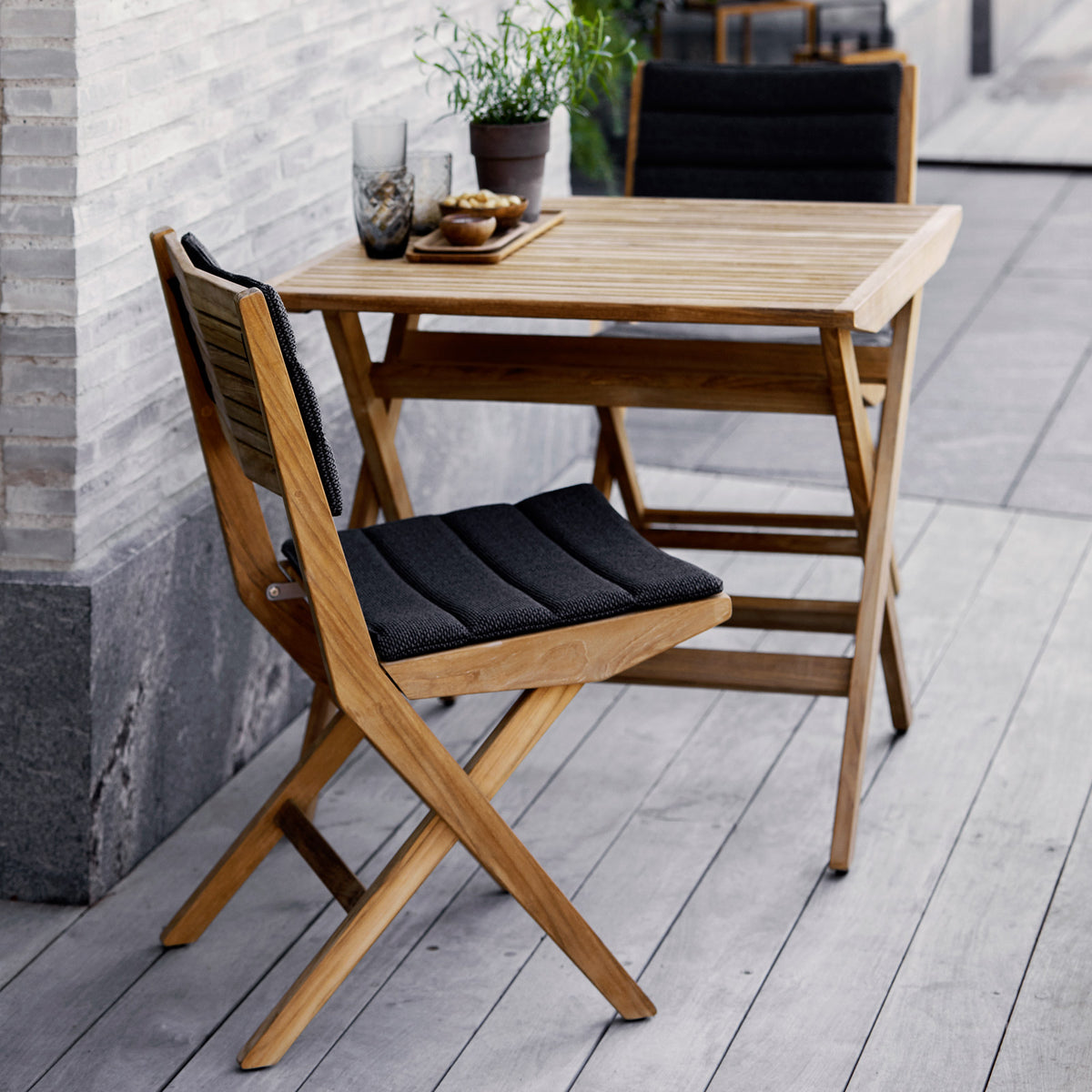 Flip Folding Teak Dining Chair by Cane-Line, showing flip folding teak dining chairs with dining table in live shot.