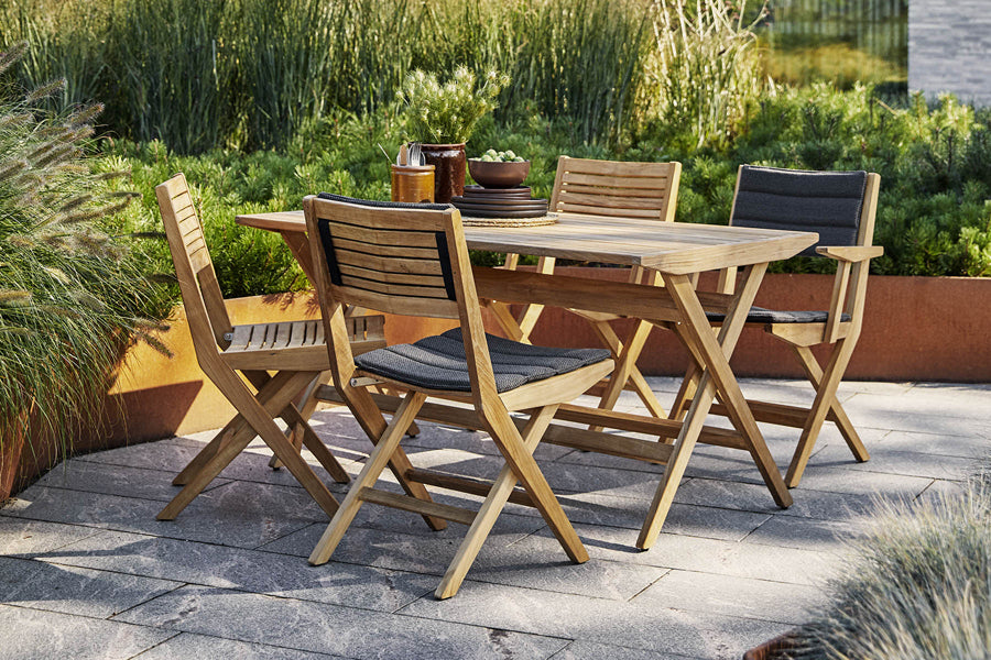 Flip Folding Teak Dining Chair by Cane-Line, showing flip folding teak dining chairs with dining table in live shot.