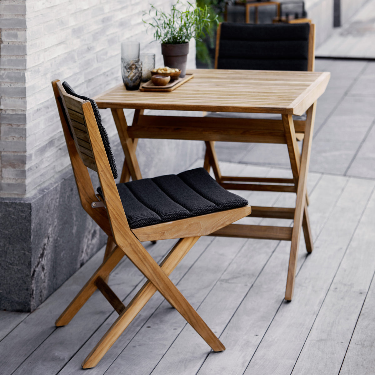 Flip Folding Teak Dining Table by Cane-Line, showing flip folding teak dining table with dining chairs in live shot.