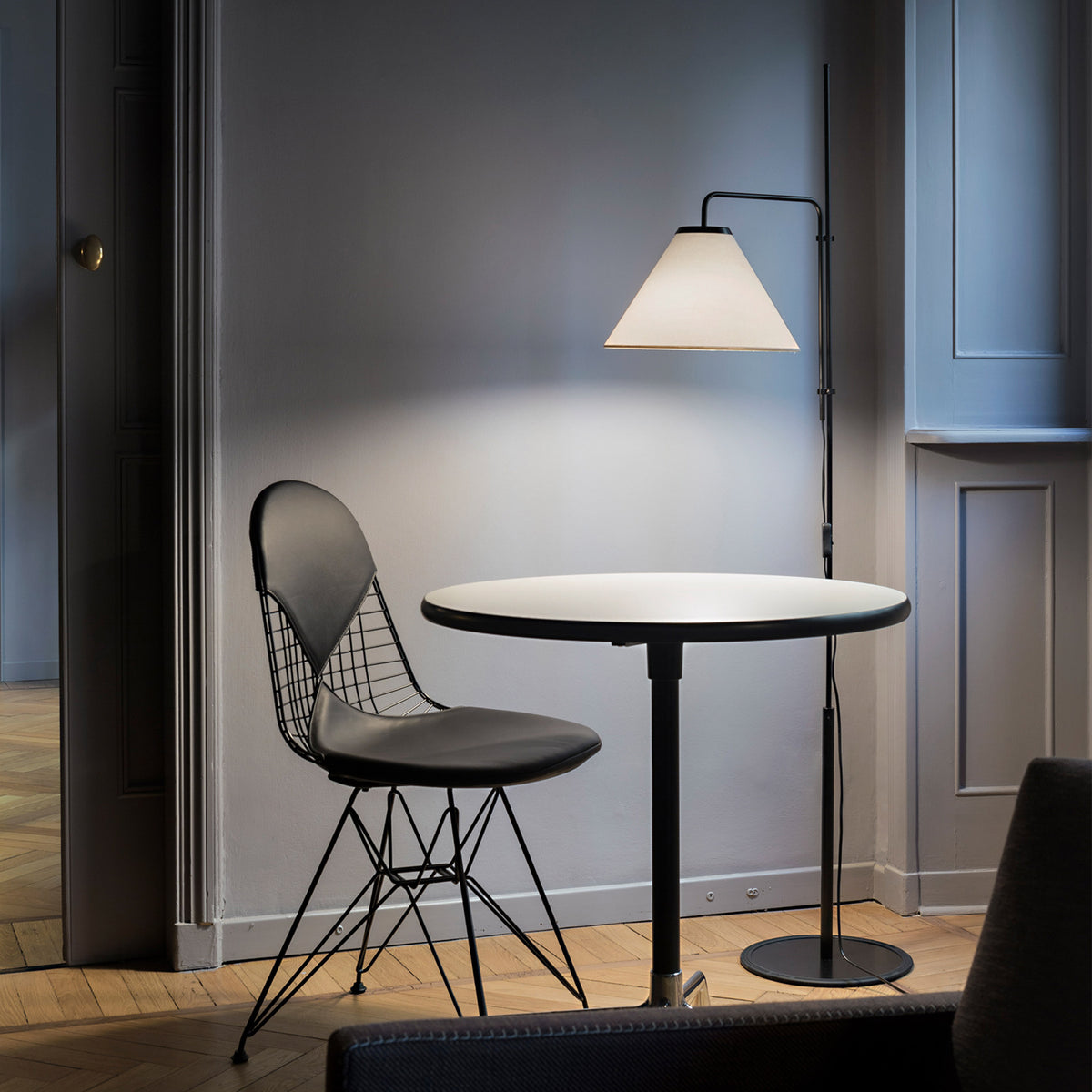 Funiculi Fabric Floor Lamp by Marset, showing funiculi fabric floor lamp with chair & table in live shot.