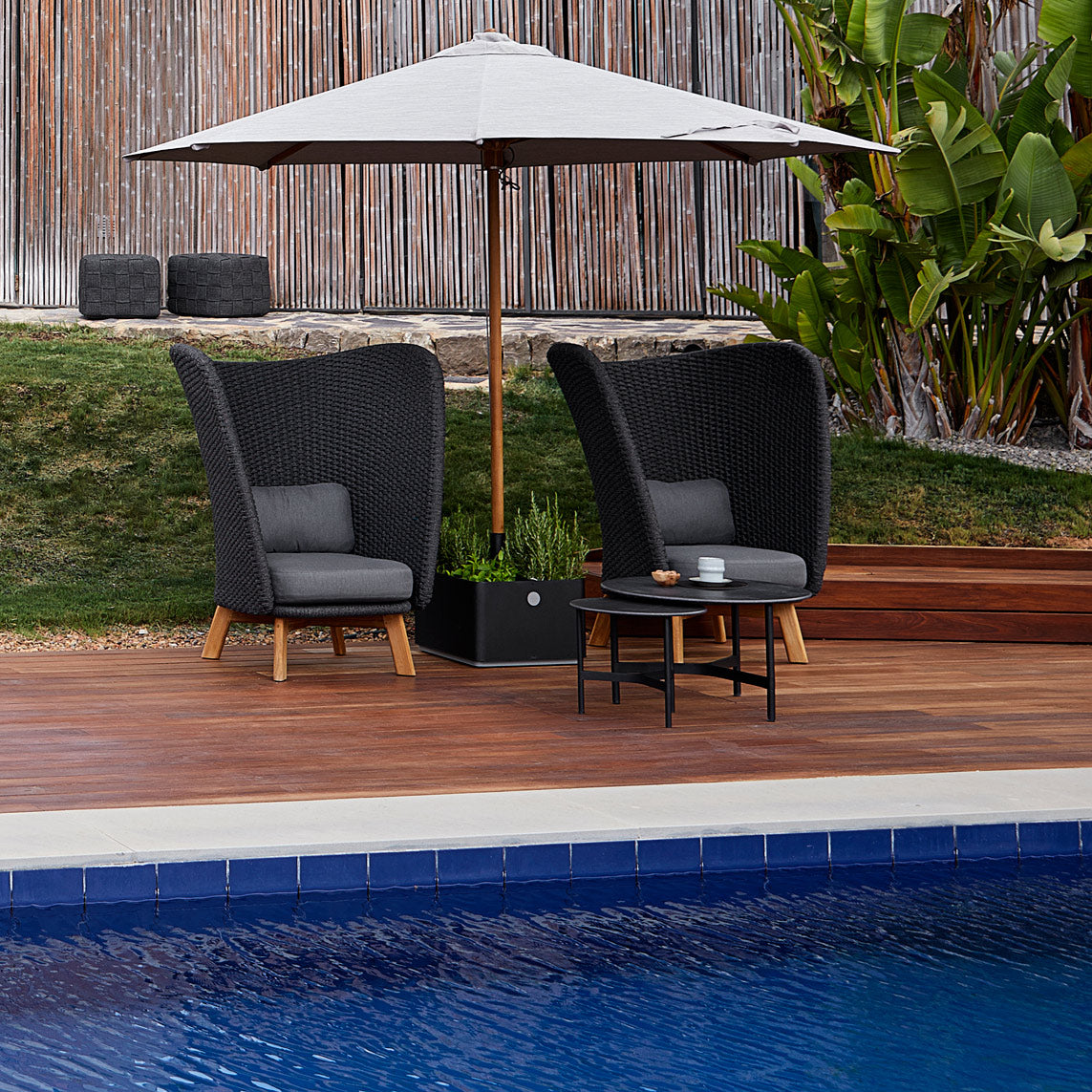 Grow Parasol Base with Wheels by Cane-Line, showing grow parasol base with parasol & chairs in live shot.