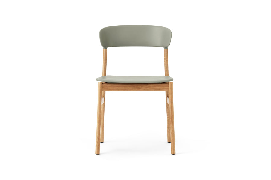 Herit Chair by Normann Copenhagen, showing front view of herit chair in oak wood legs/dusty green plastic shell seat.
