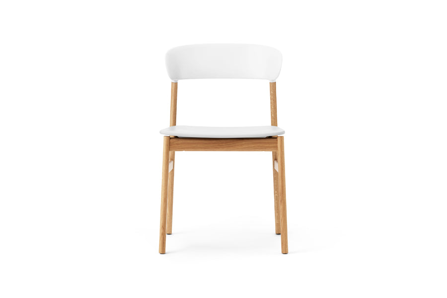 Herit Chair by Normann Copenhagen, showing front view of herit chair in oak wood legs/white plastic shell seat.