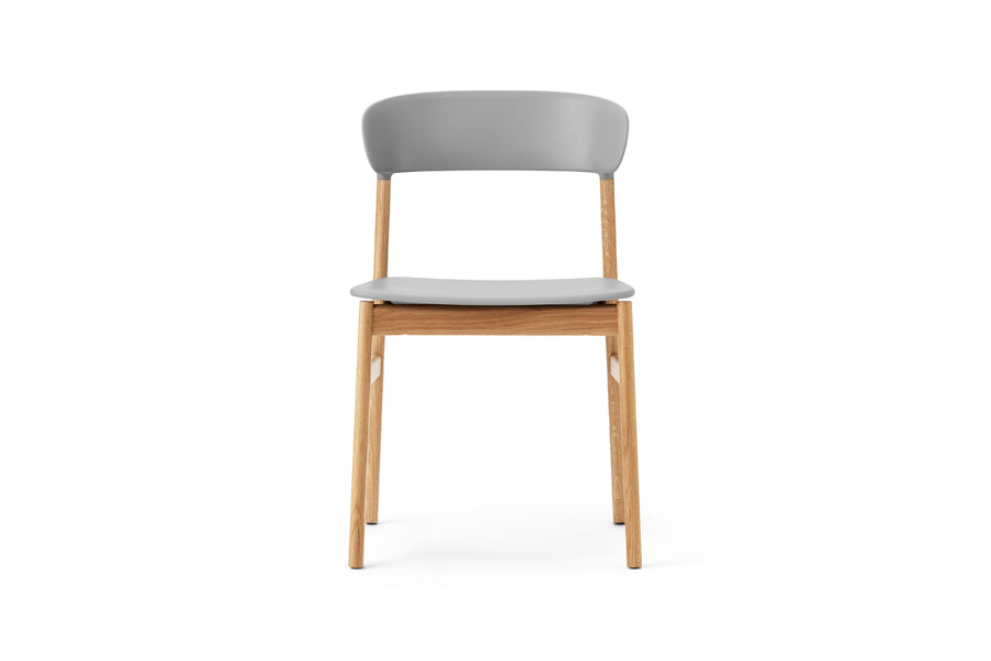 Herit Chair by Normann Copenhagen, showing front view of herit chair in oak wood legs/grey plastic shell seat.