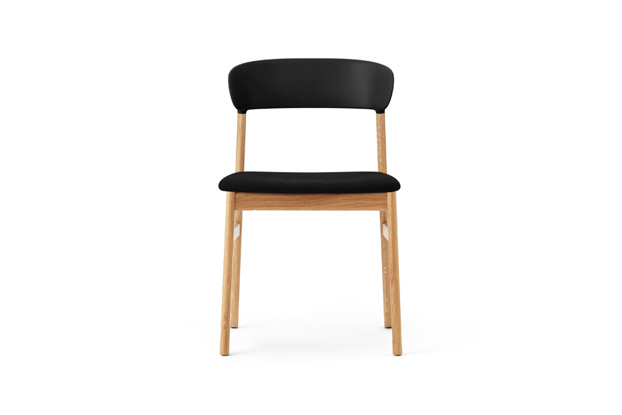 Herit Upholstery Chair by Normann Copenhagen, showing front view of herit upholstery chair in oak wood legs/black synergy fabric seat.