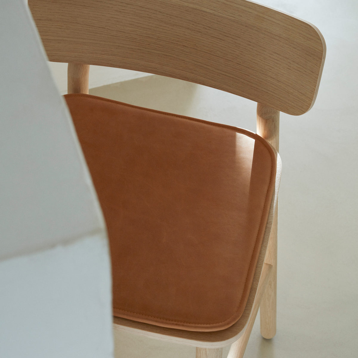 Hven Oak Low Bar Stool by Skagerak, showing top view of hven oak low bar stool with leather in live shot.