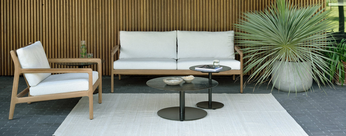 Jack Outdoor Lounge Chair by Ethnicraft, showing side view of outdoor lounge chair with two seater sofa & tables in live shot.
