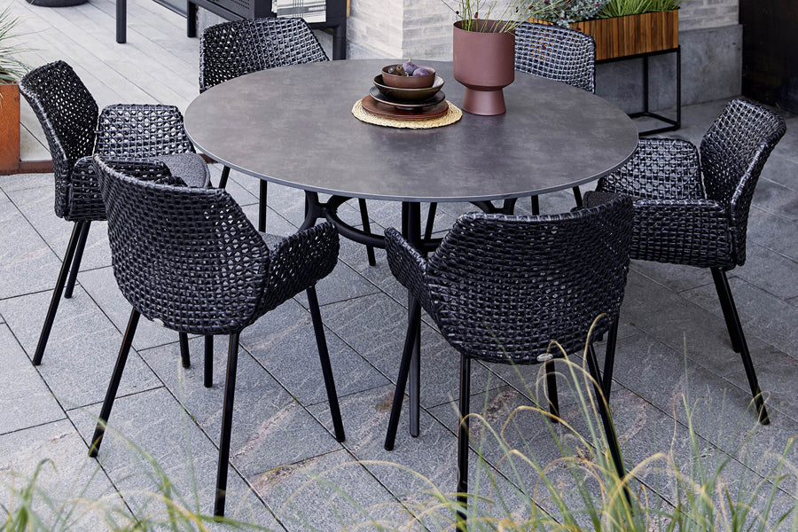 Joy Outdoor Round Dining Table by Cane-Line, showing joy outdoor round dining table with chairs in live shot.