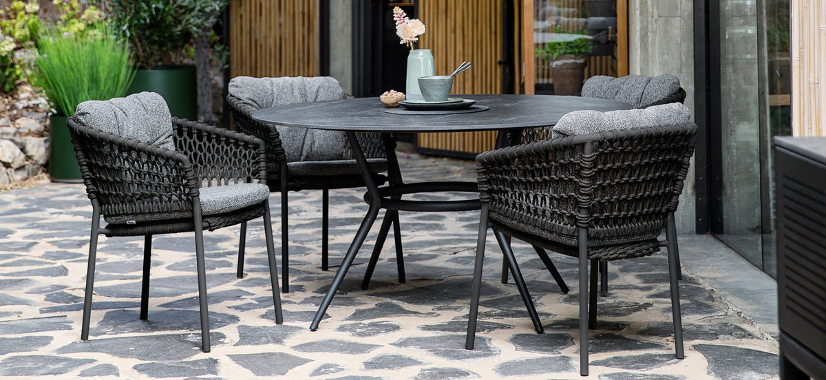 Joy Outdoor Round Dining Table by Cane-Line, showing joy outdoor round dining table with chairs in live shot.