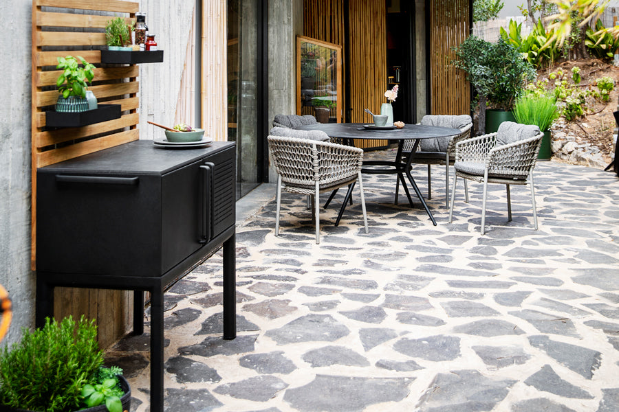 Joy Outdoor Round Dining Table by Cane-Line, showing joy outdoor round dining table with chairs in live shot.