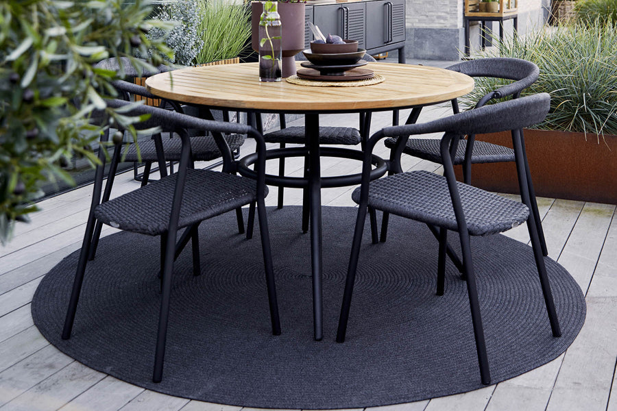 Joy Outdoor Round Dining Table by Cane-Line, showing joy outdoor round dining table with chairs in live shot.