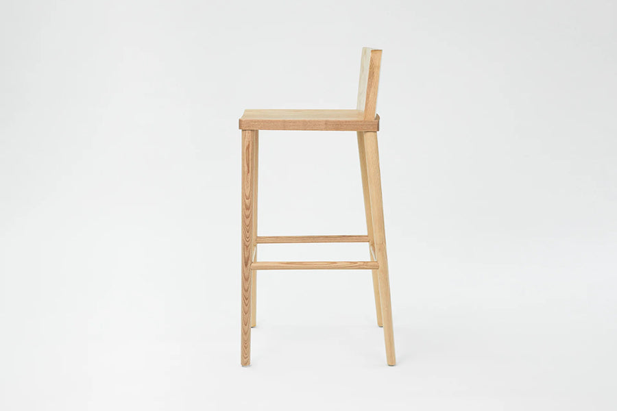 LAX Milk Stool by MASHstudios, showing side view of lax milk stool in bar/solid ash wood.