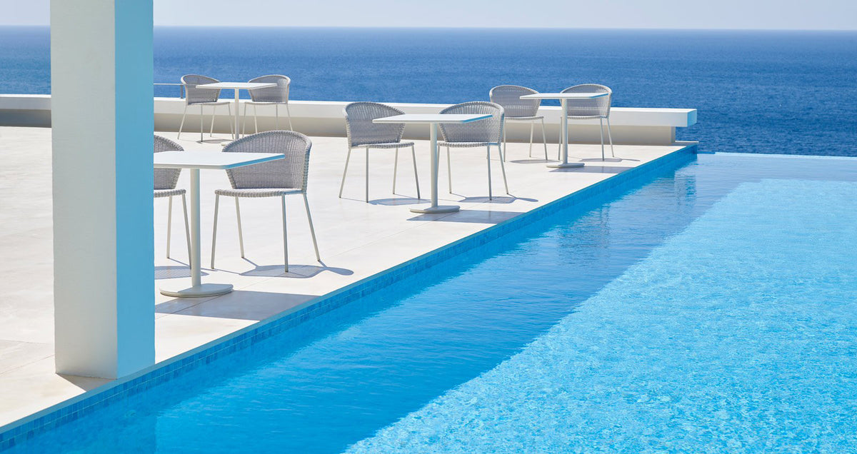 Lean Stackable Dining Chair by Cane-Line, showing lean stackable dining chairs with tables in live shot.