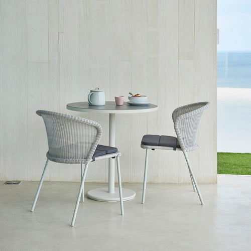 Lean Stackable Dining Chair by Cane-Line, showing lean stackable dining chairs with table in live shot.