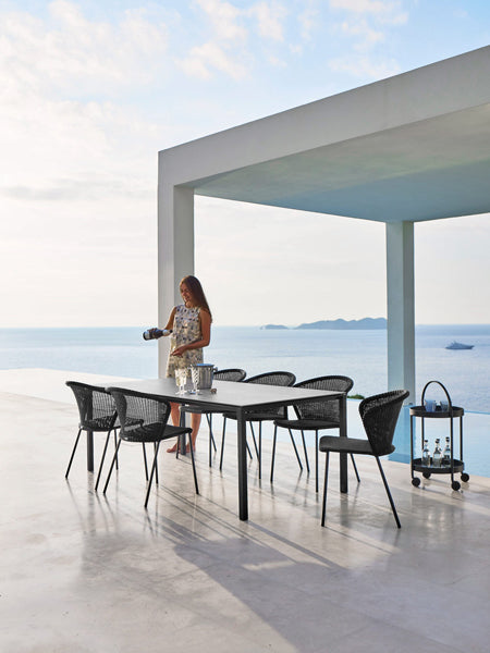 Lean Stackable Dining Chair by Cane-Line, showing lean stackable dining chairs with table in live shot.