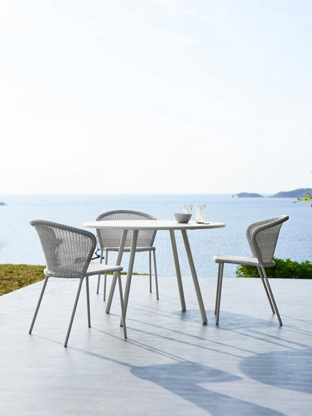 Lean Stackable Dining Chair by Cane-Line, showing lean stackable dining chairs with table in live shot.