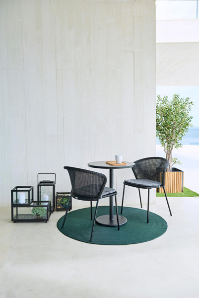 Lean Stackable Dining Chair by Cane-Line, showing lean stackable dining chairs with table in live shot.