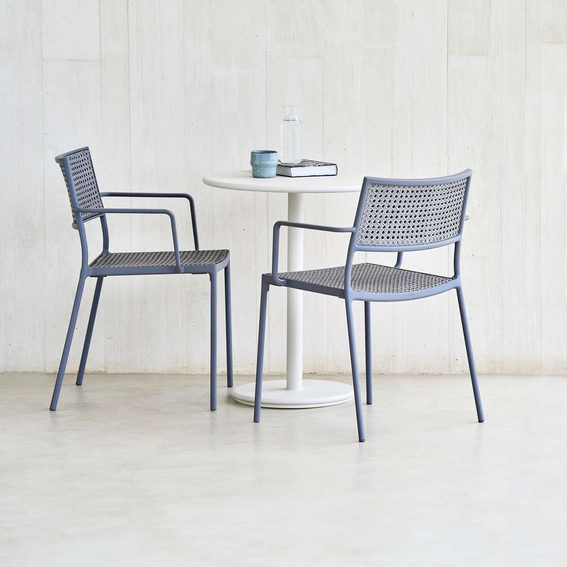 Less Stackable Dining Armchair by Cane-Line, showing less stackable dining armchairs with table in live shot.