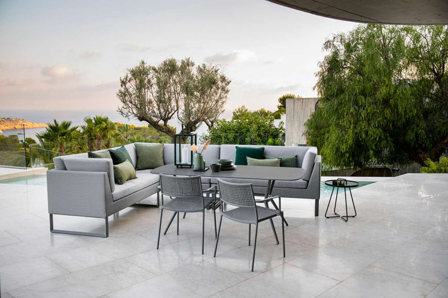 Less Stackable Dining Armchair by Cane-Line, showing less stackable dining armchairs with table in live shot.