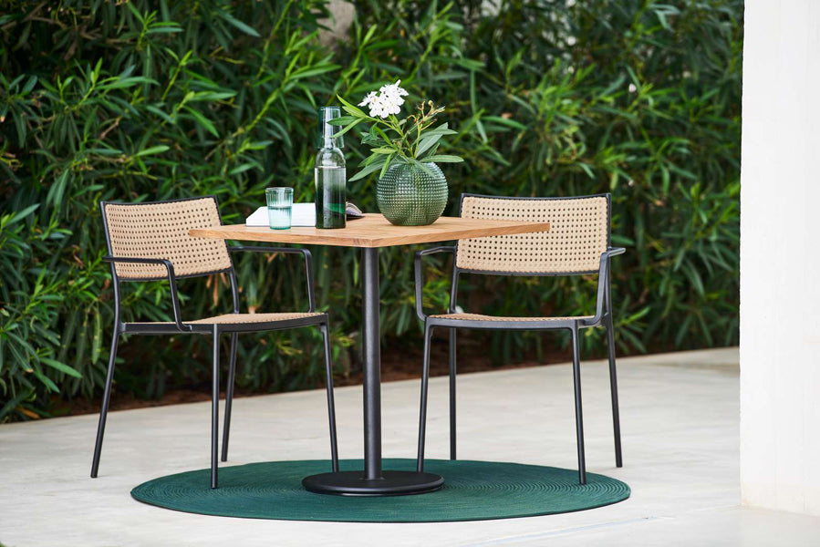 Less Stackable Dining Armchair by Cane-Line, showing less stackable dining armchairs with table in live shot.