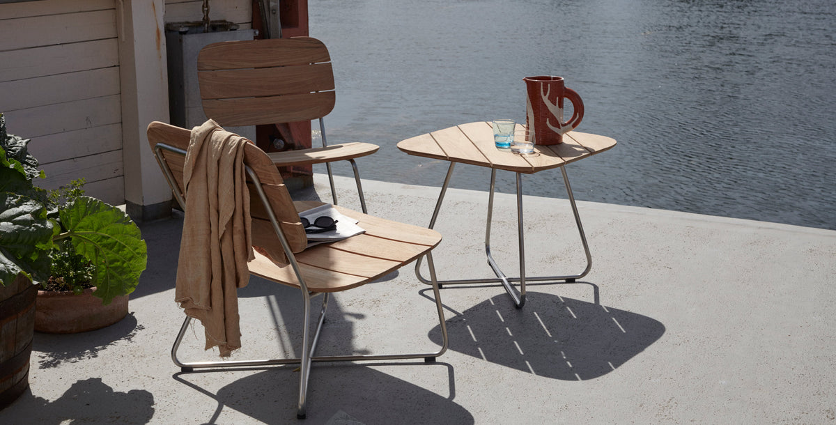 Lilium Teak Lounge Table by Skagerak, showing lilium teak lounge table with lounge chairs in live shot.