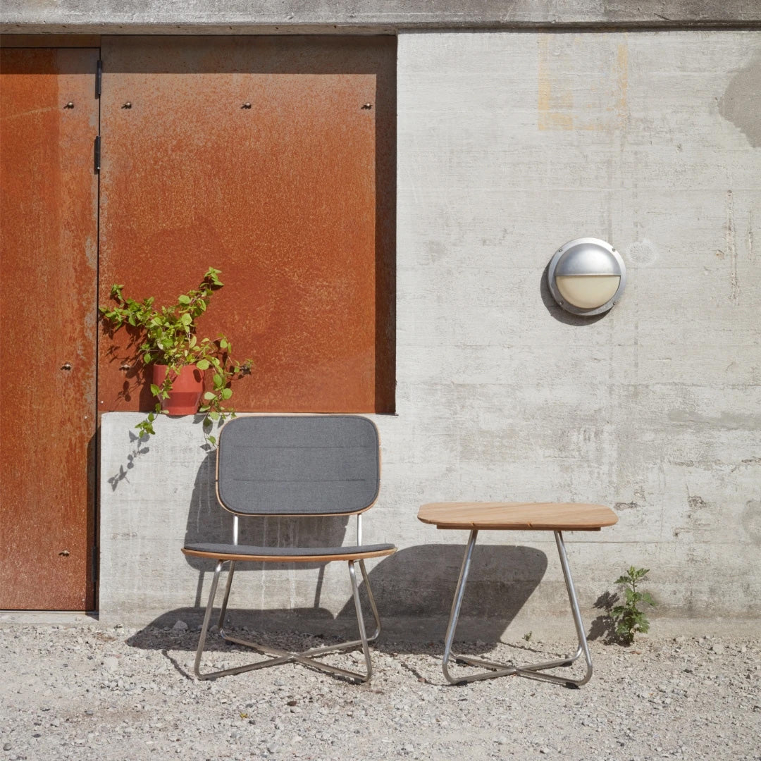 Lilium Teak Lounge Table by Skagerak, showing lilium teak lounge table with cushion lounge chair in live shot.