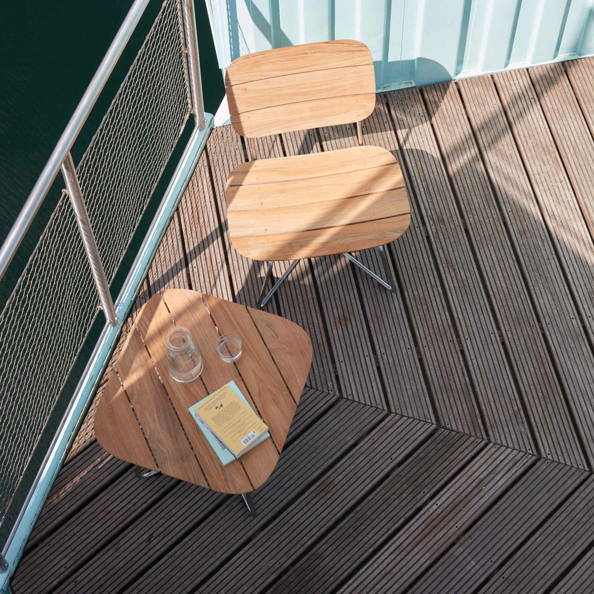 Lilium Teak Lounge Table by Skagerak, showing lilium teak lounge table with lounge chair in live shot.
