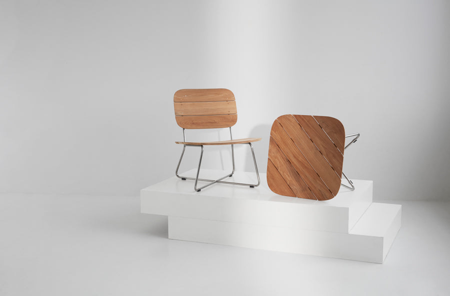 Lilium Teak Lounge Table by Skagerak, showing lilium teak lounge table with lounge chair in live shot.