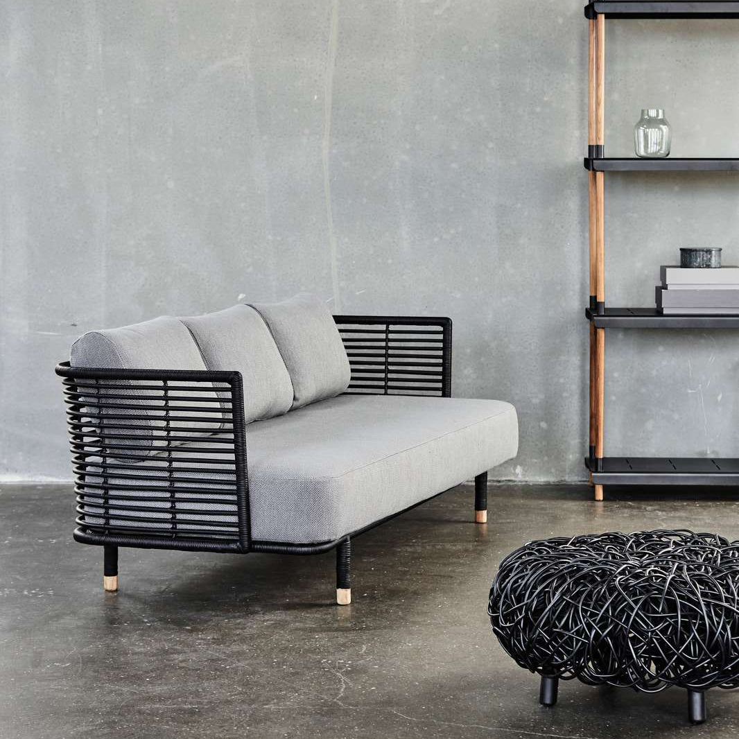 Loop Footstool by Cane-Line, showing loop footstool with sofa in live shot.