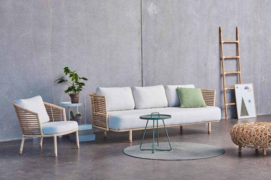 Loop Footstool by Cane-Line, showing loop footstool with sofa, table, rug & chair in live shot.