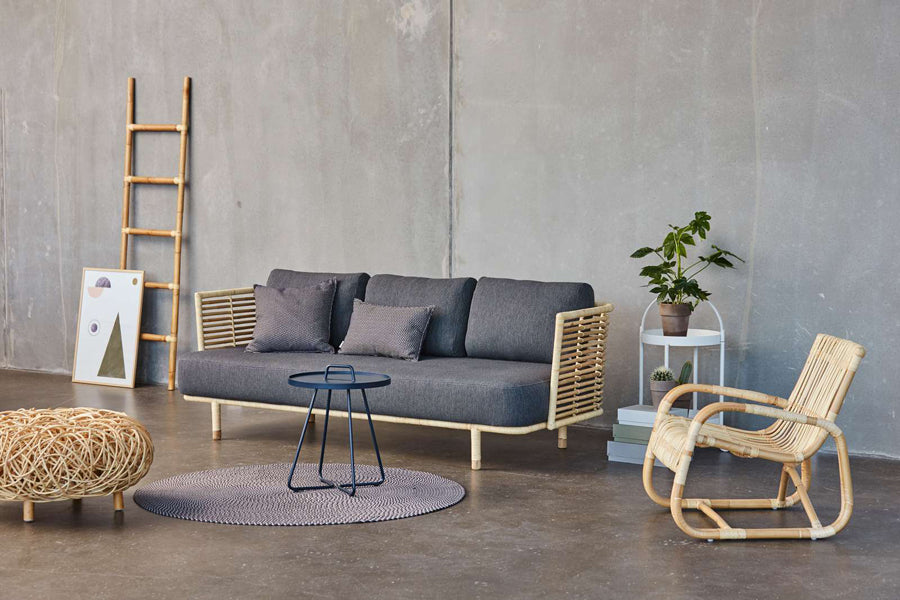 Loop Footstool by Cane-Line, showing loop footstool with sofa, table, rug & chair in live shot.