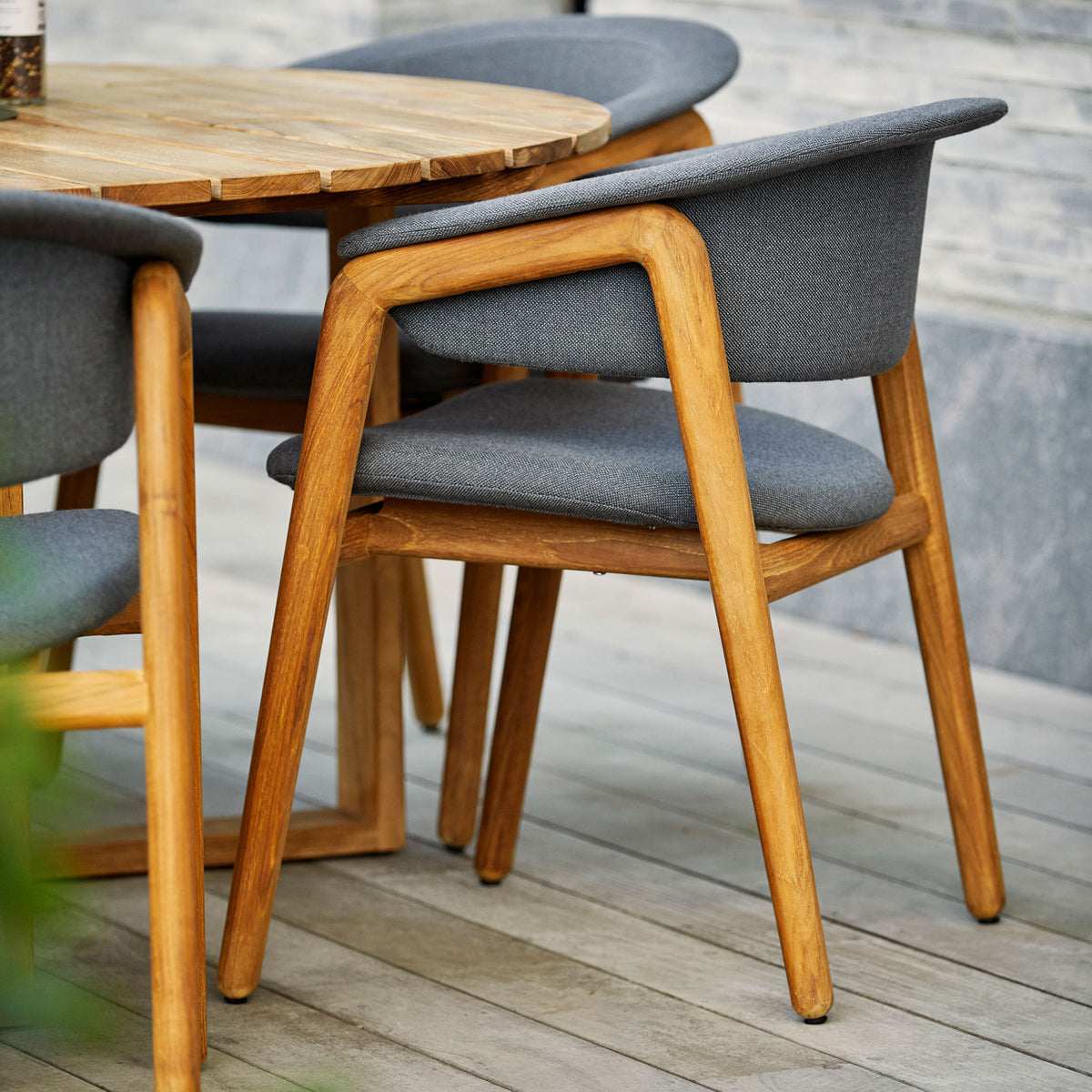Luna Dining Chair by Cane-Line, showing luna dining chairs with table in live shot.