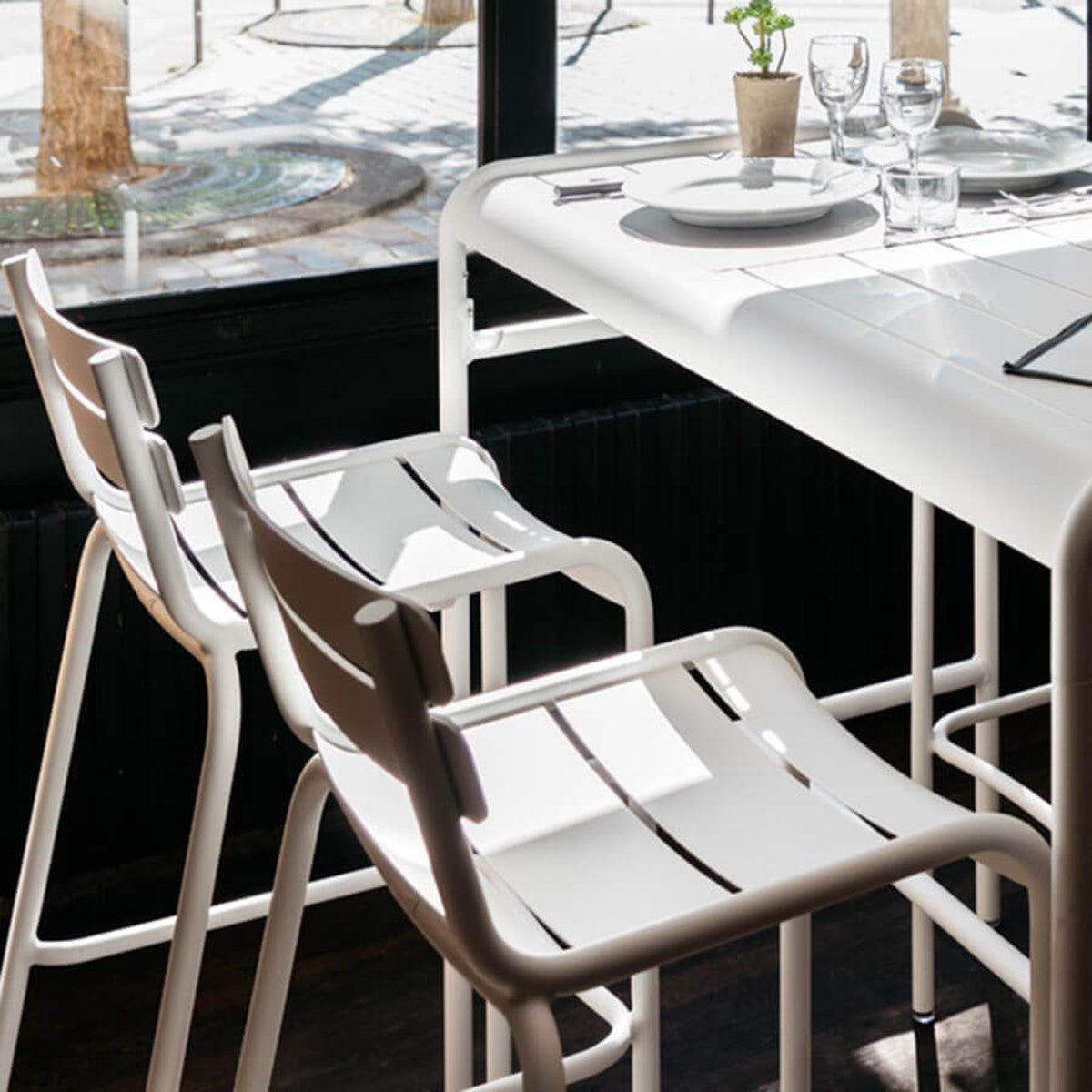 Luxembourg High Chair by Fermob, showing side view of high chairs with table in live shot.