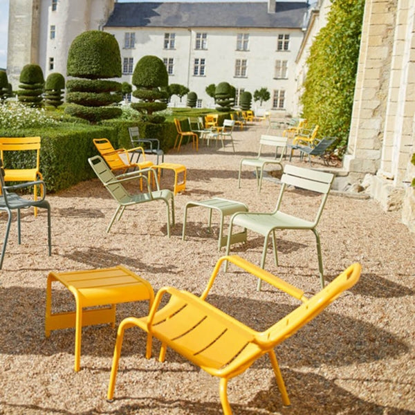 Luxembourg Low Armchair by Fermob, showing low armchairs with end tables in live shot.