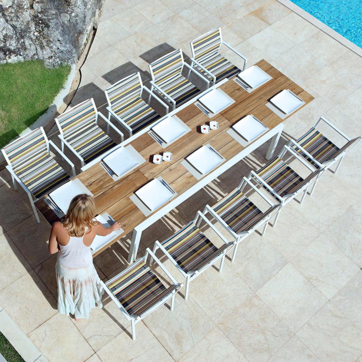 Baia Teak Aluminum Extendable Dining Table by Mamagreen, showing baia teak aluminum extendable dining table with stripe stackable armchair in live shot.
