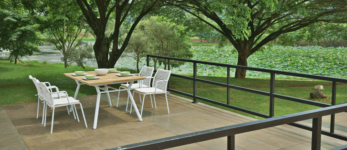 Manda Aluminum Stackable Woven Dining Chair by Mamagreen, showing group of manda aluminum stackable woven dining chair with manda teak dining table in live shot.