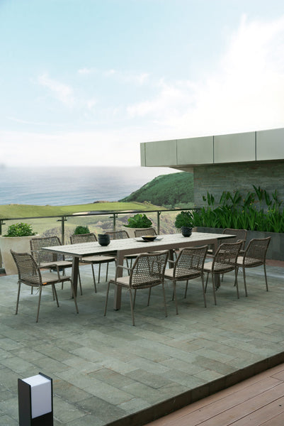 Manda Aluminum Stackable Woven Dining Chair by Mamagreen, showing group of manda aluminum stackable woven dining chair with baia extension dining table in live shot.