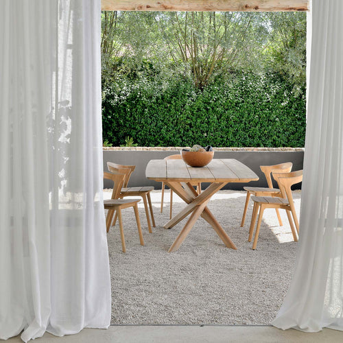 Mikado Outdoor Dining Table by Ethnicraft, showing outdoor dining table with chairs in live shot.