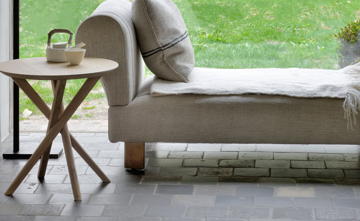 Mikado Side Table by Ethnicraft, showing front view of side table with sofa in the live shot.