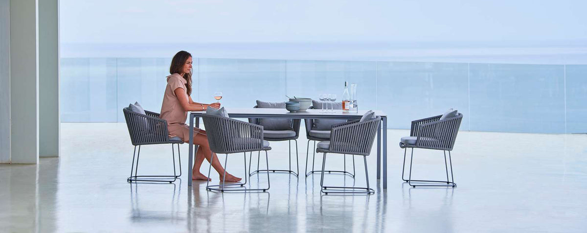 Moments Dining Armchair by Cane-Line, showing moments dining armchairs with table in live shot.