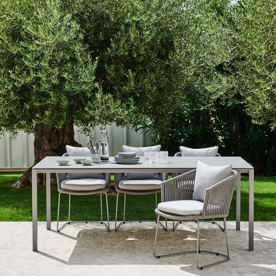 Moments Dining Armchair by Cane-Line, showing moments dining armchairs with table in live shot.