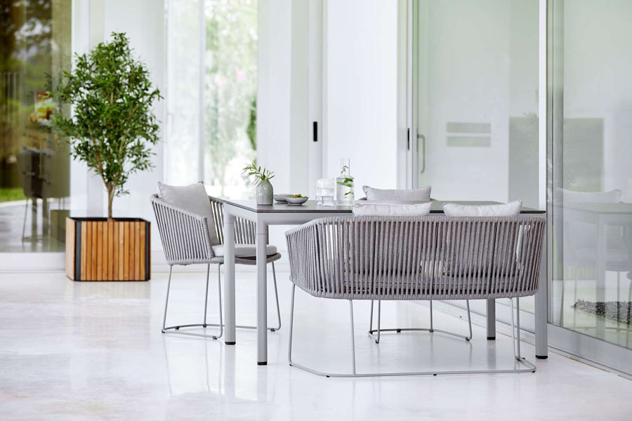 Moments Dining Armchair by Cane-Line, showing moments dining armchairs with table & bench in live shot.