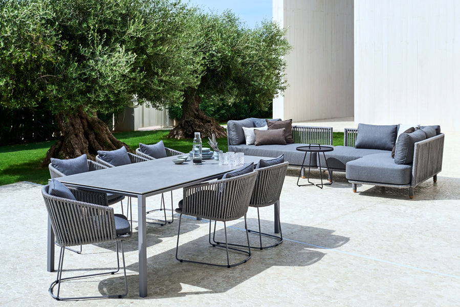 Moments Dining Armchair by Cane-Line, showing moments dining armchairs with table & sectional in live shot.