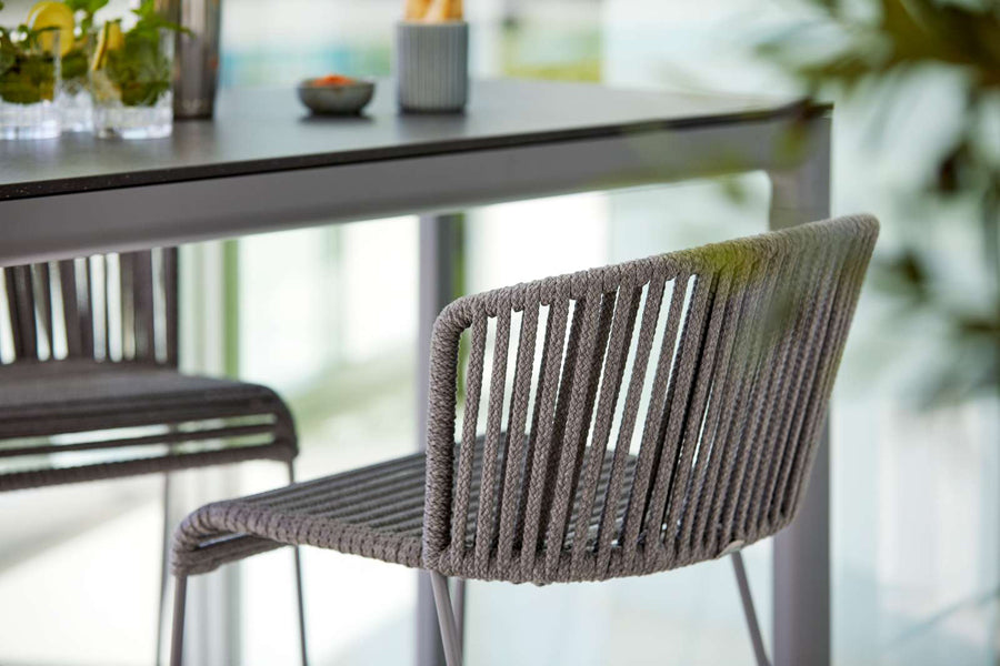 Moments Outdoor Bar Stool by Cane-Line, showing moments outdoor bar stools with table in live shot.