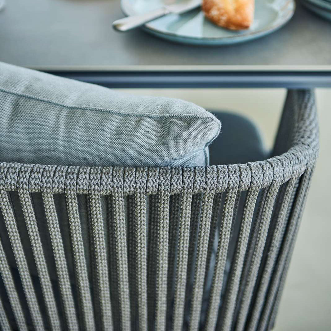 Moments Outdoor Dining Bench by Cane-Line, showing closeup back view of moments outdoor dining bench with table in live shot.