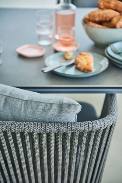 Moments Stackable Dining Armchair by Cane-Line, showing closeup view of moments stackable dining armchair in live shot.