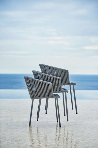 Moments Stackable Dining Armchair by Cane-Line, showing moments stackable dining armchairs in live shot.