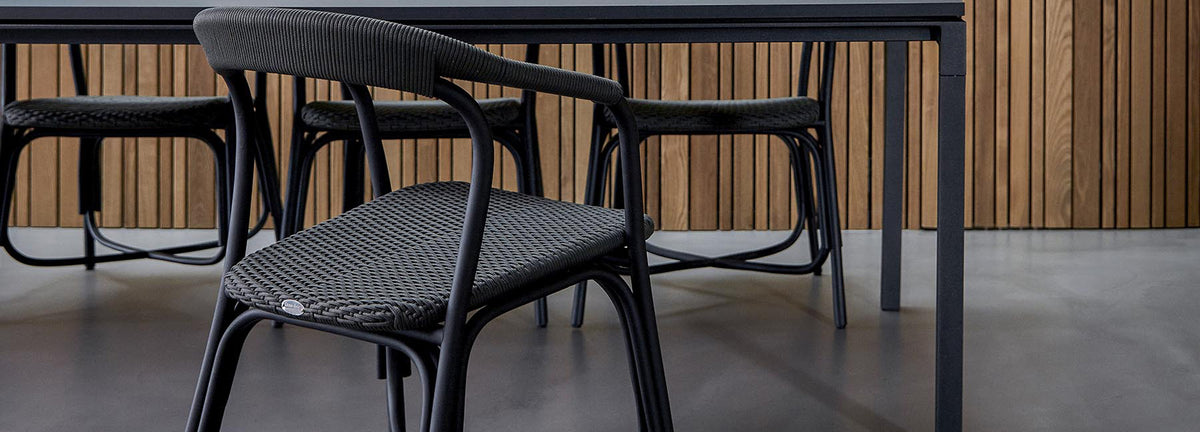 Noble Indoor Armchair by Cane-Line, showing noble indoor armchairs with table in live shot.