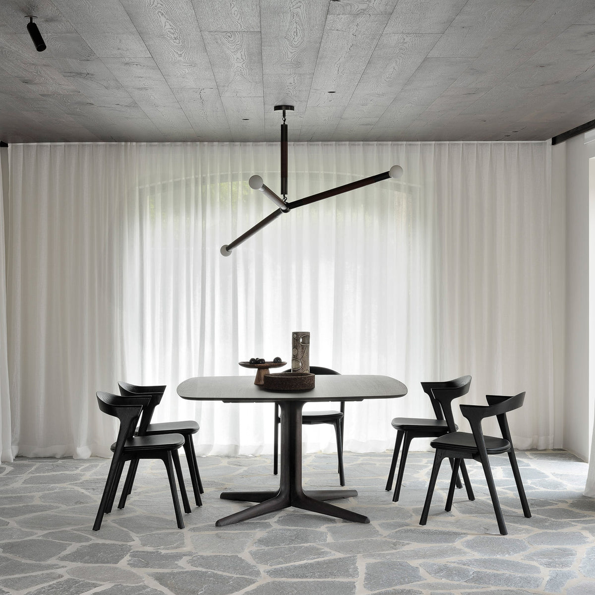 Corto Dining Table by Ethnicraft, showing corto dining table with chairs in live shot.