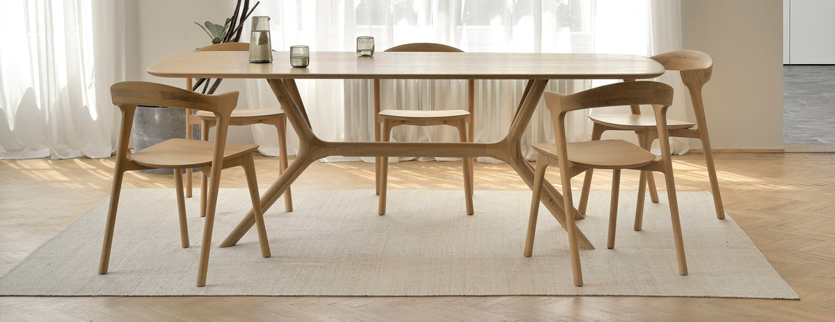 X Dining Table by Ethnicraft, showing oak x dining table with chairs in live shot.